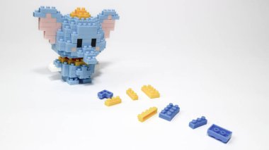 Beyaz arka planda plastik yapı taşlarından yapılmış şirin mavi bir fil figürü. Renkli yapı taşlarıyla yapılmış oyuncak bir fil. Minimalist bir stüdyo resmi..