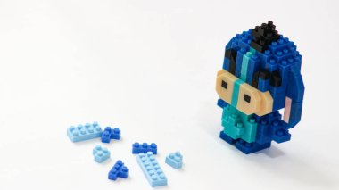 Plastik tuğlalardan yapılmış, beyaz arka planda minimalist tarzda izole edilmiş şirin mavi blok oyuncağı karakteri. Birbirine kenetlenmiş bloklardan inşa edilmiş küçük mavi pikselli biblo, temiz beyaz arka planda yaratıcı oyuncak tasarımı.