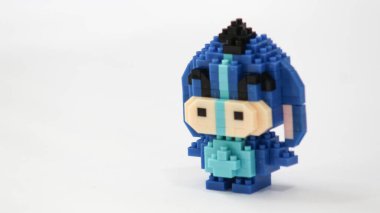 Plastik tuğlalardan yapılmış, beyaz arka planda minimalist tarzda izole edilmiş şirin mavi blok oyuncağı karakteri. Birbirine kenetlenmiş bloklardan inşa edilmiş küçük mavi pikselli biblo, temiz beyaz arka planda yaratıcı oyuncak tasarımı.