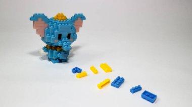 Beyaz arka planda plastik yapı taşlarından yapılmış şirin mavi bir fil figürü. Renkli yapı taşlarıyla yapılmış oyuncak bir fil. Minimalist bir stüdyo resmi..