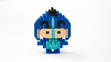 Plastik tuğlalardan yapılmış, beyaz arka planda minimalist tarzda izole edilmiş şirin mavi blok oyuncağı karakteri. Birbirine kenetlenmiş bloklardan inşa edilmiş küçük mavi pikselli biblo, temiz beyaz arka planda yaratıcı oyuncak tasarımı.