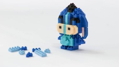 Plastik tuğlalardan yapılmış, beyaz arka planda minimalist tarzda izole edilmiş şirin mavi blok oyuncağı karakteri. Birbirine kenetlenmiş bloklardan inşa edilmiş küçük mavi pikselli biblo, temiz beyaz arka planda yaratıcı oyuncak tasarımı.