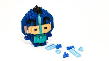 Plastik tuğlalardan yapılmış, beyaz arka planda minimalist tarzda izole edilmiş şirin mavi blok oyuncağı karakteri. Birbirine kenetlenmiş bloklardan inşa edilmiş küçük mavi pikselli biblo, temiz beyaz arka planda yaratıcı oyuncak tasarımı.