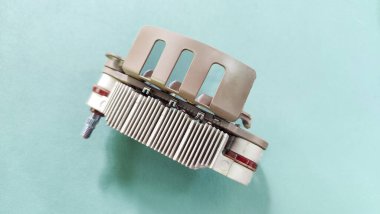 Yeşil arka planda metal ısı gidericisi olan bir otomotiv alternatörü. Elektronik otomobil alternatör diyot köprü bileşenleri temiz yeşil bir yüzey üzerinde izole edilir..