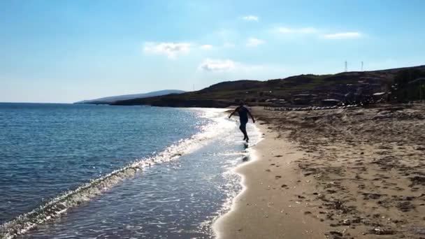 L'homme heureux court sur la plage à la camera.Slow motion.Throwing sable et frapper les vagues . — Video