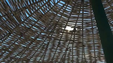 Güneş fişekleri hasır şemsiye arkasında yapıyor.