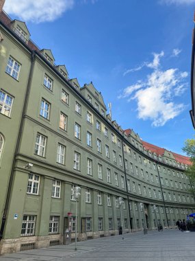 Mavi gökyüzünün altında sayısız penceresi olan kıvrımlı yeşil bina