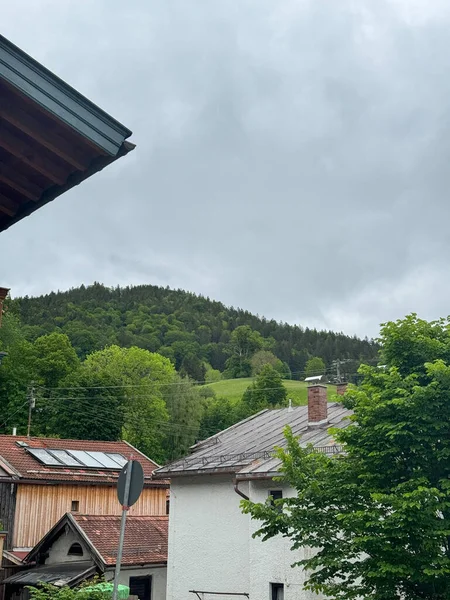 yemyeşil bir dağın altındaki evlerin çatıları