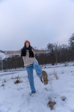 Kış manzarasında kar tekmeleyen neşeli kadın.