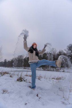 Kış parkında karda oynayan neşeli kadın.