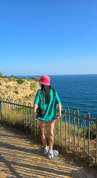 Atletik kadın uçurumdan nefes kesici deniz manzarası seyrediyor.