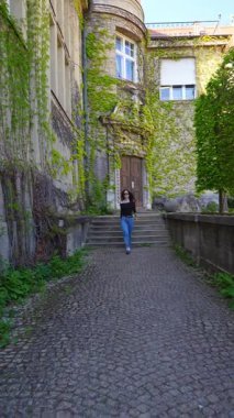 Avrupa avlusunda kameraya doğru yürürken güneş gözlüğünü çıkaran zarif bir kadın.