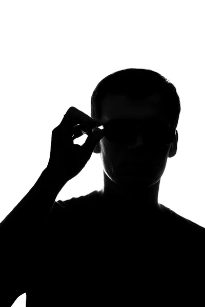 Młody człowiek myśli, trzymając okulary — Zdjęcie stockowe