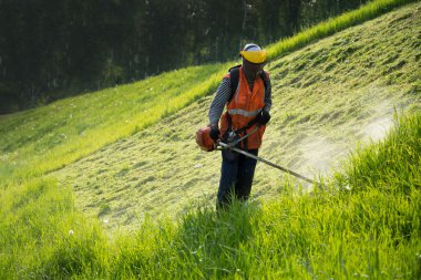 Bir üniforma ve maske içinde çalışan bir çimlere keser