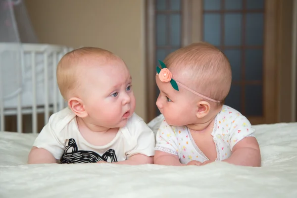 2つの美しい赤ちゃんがベッドの上に横たわって、お互いを見て — ストック写真