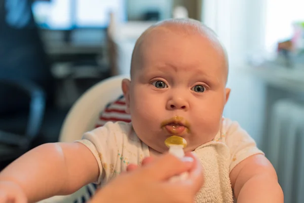 Bebé niño se sienta en una silla y comer —  Fotos de Stock