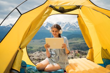 kız müzik ve Tablet vasıl seyir kulaklıklar ile çadırda