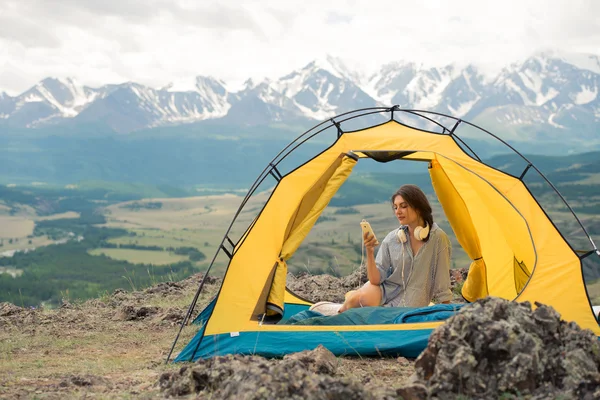 Chica bonita se sienta en una tienda de campaña en la montaña — Foto de Stock