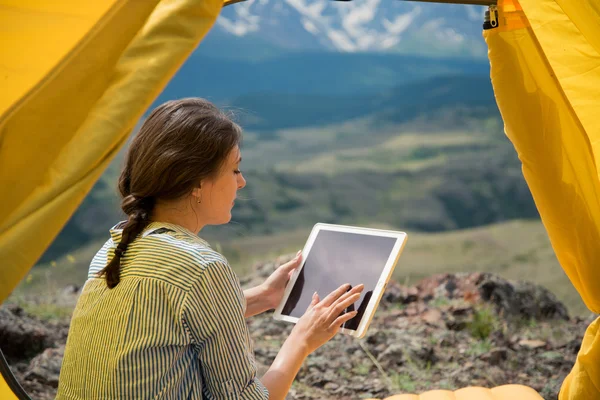 Lány keres hegyi alapon tablet sátorban — Stock Fotó