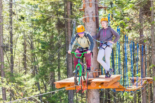 girl climbs into ropes course. bike