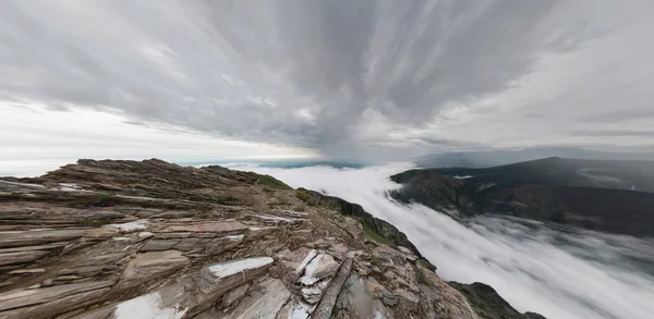 Um homem está nas montanhas e olha para a distância, acima — Fotografia de Stock