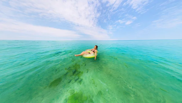 Chica en anillo inflable flotando en el mar azul — Foto de Stock
