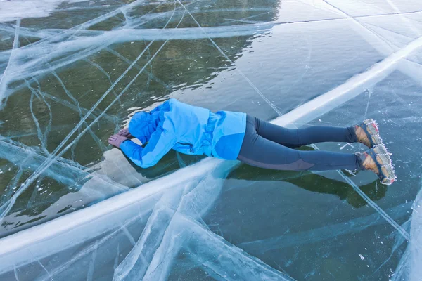 Girl in blue jacket lying on the ice of Lake Baikal — Stock Photo, Image