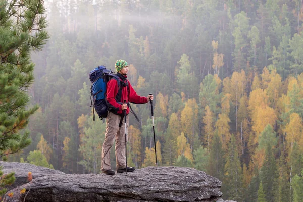 Mann mit Rucksack und Trekkingstock im Kopftuch auf einem Roc stehend — Stockfoto