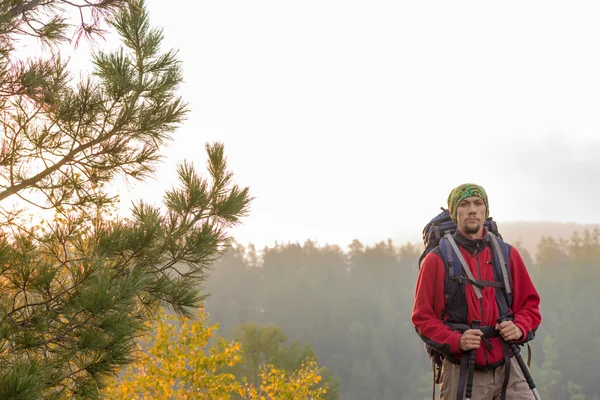 Mann mit Rucksack und Trekkingstock im Kopftuch auf einem Roc stehend — Stockfoto