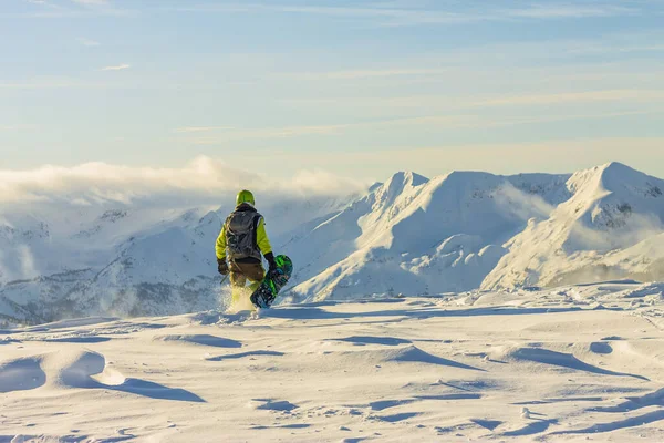 Snowboarder freerider is standing in the snowy mountains in winter under the clouds — Stock Photo, Image