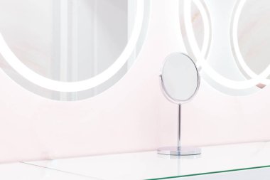 Aydınlatılmış yansımalı yuvarlak aynalar, modern tasarım pastel mavi ve pembe. Güzellik stüdyosunda stilize edilmiş.