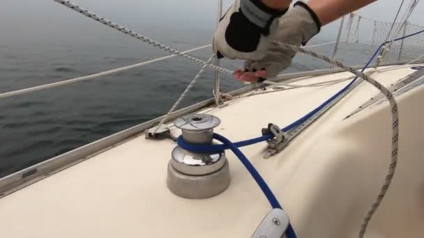 Voile, homme tirant des cordes, enroulant des feuilles autour de treuils. Gros plan. temps réel — Video