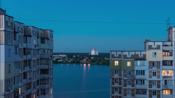 Timelapse. Ventana vista al lago. La vista desde las ventanas de dos edificios altos. En la calle llega la noche . — Vídeo de stock