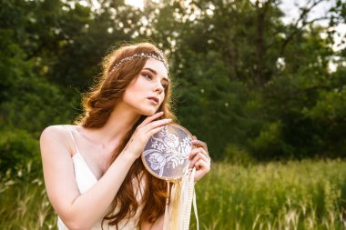 Kızıl saçlı genç kız ormanda. Parkta gelin portresi. Kız holding koruyucusu. hippi kız