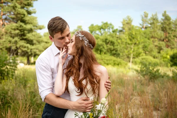 The couple in the ears of wheat in forest. The bride and groom in the wheat ears in the Park.