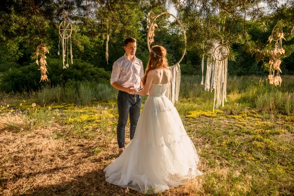 O casal nas orelhas de trigo na floresta. A noiva e o noivo nas orelhas de trigo no Parque . — Fotografia de Stock