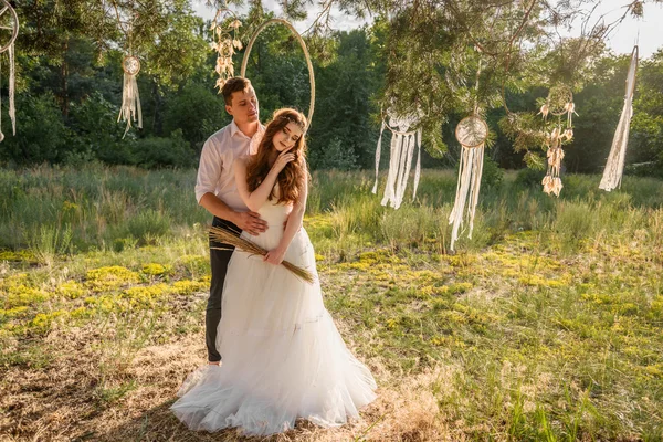 O casal nas orelhas de trigo na floresta. A noiva e o noivo nas orelhas de trigo no Parque . — Fotografia de Stock