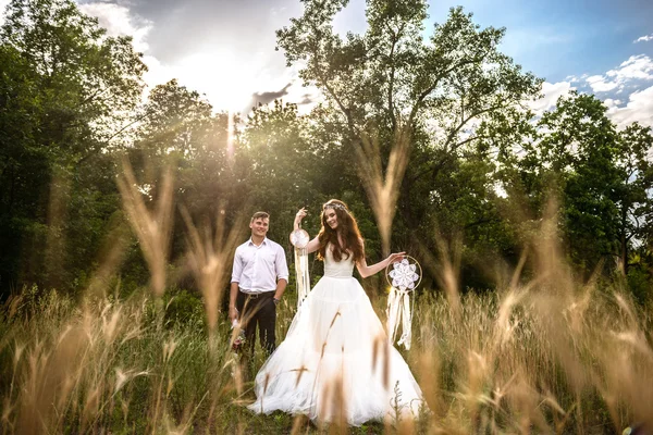 O casal nas orelhas de trigo na floresta. A noiva e o noivo nas orelhas de trigo no Parque . — Fotografia de Stock