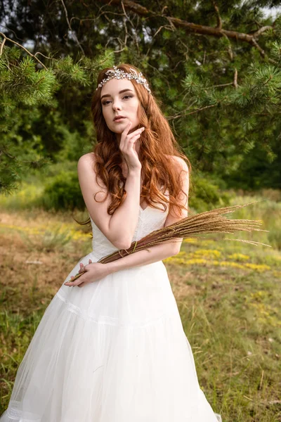 Rapariga ruiva na floresta. Retrato da noiva no Parque. Uma menina segura as orelhas de trigo nas mãos . — Fotografia de Stock