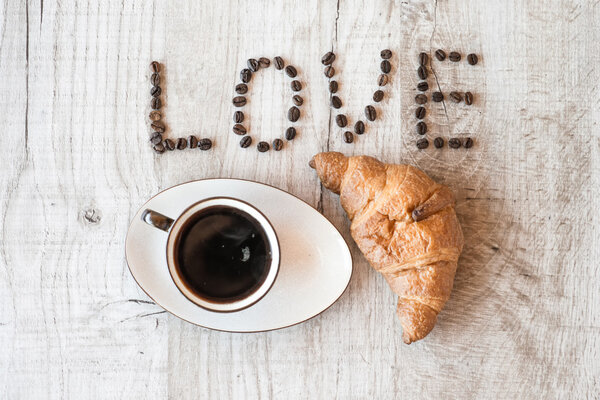 Cup of coffee with croissant on wooden background. title i love coffee.