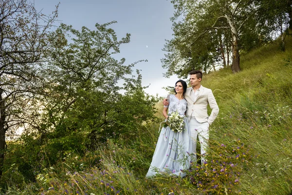 Ungt par i kärlek utomhus. Eleganta brudparet poserar tillsammans utomhus på en bröllopsdag. bruden och brudgummen i parken. Ungt par i skogen. Ungt par i gräset. par promenader — Stockfoto