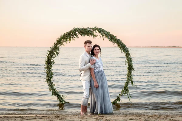 Jovem casal em uma praia ao pôr do sol — Fotografia de Stock