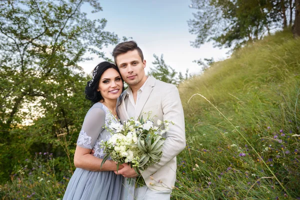 Casal jovem no amor ao ar livre. Noiva elegante e noivo posando juntos ao ar livre em um dia de casamento. noiva e noivo no Parque. jovem casal na floresta. jovem casal na grama. casal caminhando — Fotografia de Stock