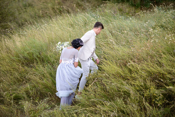 Young couple in love outdoor. Elegant bride and groom posing together outdoors on a wedding day. bride and groom in the Park. young couple in the woods. young couple in the grass. couple walking 