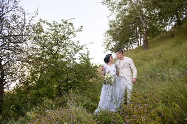 Casal jovem no amor ao ar livre. Noiva elegante e noivo posando juntos ao ar livre em um dia de casamento. noiva e noivo no Parque. jovem casal na floresta. jovem casal na grama. casal caminhando — Fotografia de Stock