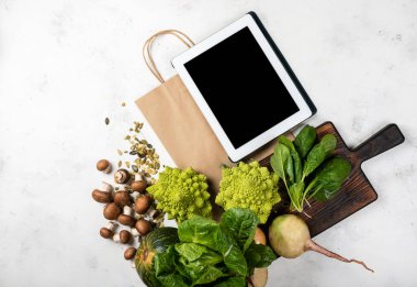 Tablet bilgisayar kağıdı alışveriş çantası ve doğranmış taze sebzeler. Bakkal çevrimiçi kavramı