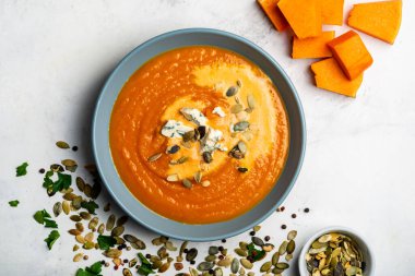 Beyaz arka planda peynir ve çekirdekli kabak kremalı çorba. Üst görünüm