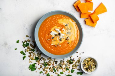 Beyaz arka planda küflü peynirli ve tohumlu balkabağı kremalı çorba. Üst görünüm