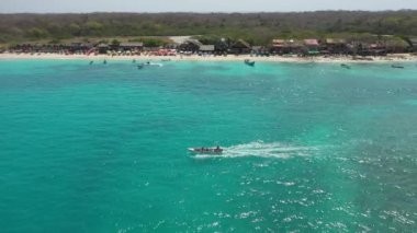 Bir zevk teknesi turistleri kumlu bir tropikal sahil havası manzarası boyunca gezintiye çıkarır..