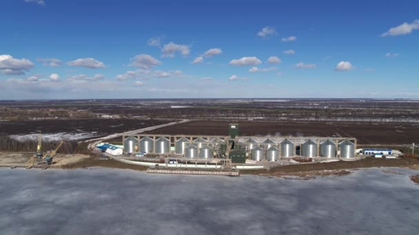 Agro-usine de transformation et silos pour le nettoyage à sec et le stockage de produits agricoles, farine, céréales et céréales avec de beaux nuages et rivière gelée en hiver — Video